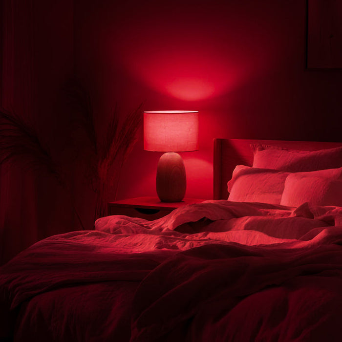 Chromalux Unwind Red Incandescent Light Bulb For Sleep illuminating a cozy red bedroom with a bedside lamp.