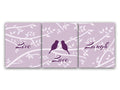 A set of three purple art prints with the words 'Love', 'Laugh', and 'Love' printed on them, arranged vertically. The center print has two love birds facing each other while sitting on a branch. The light purple background features a white silhouette branch pattern, with white leaves.