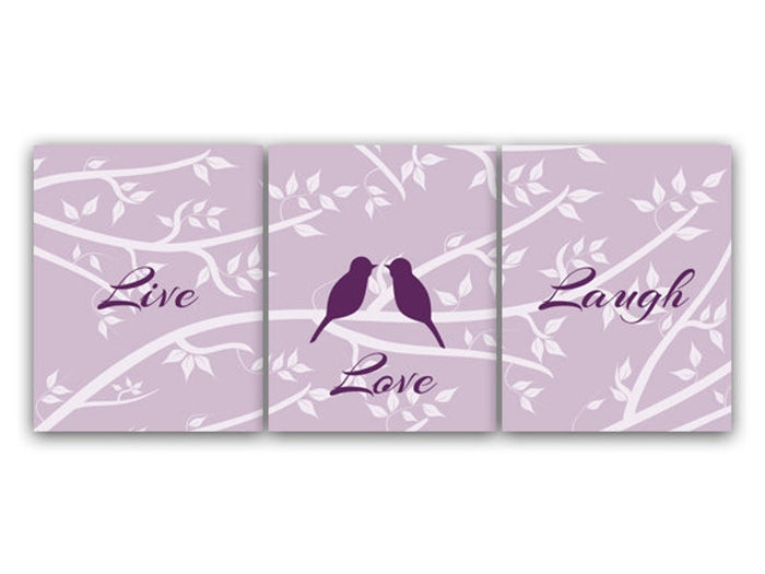 A set of three purple art prints with the words 'Love', 'Laugh', and 'Love' printed on them, arranged vertically. The center print has two love birds facing each other while sitting on a branch. The light purple background features a white silhouette branch pattern, with white leaves.